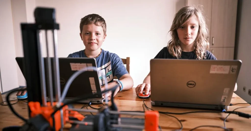 Žáci ZŠ Prameny sedí v učebně s notebooky.