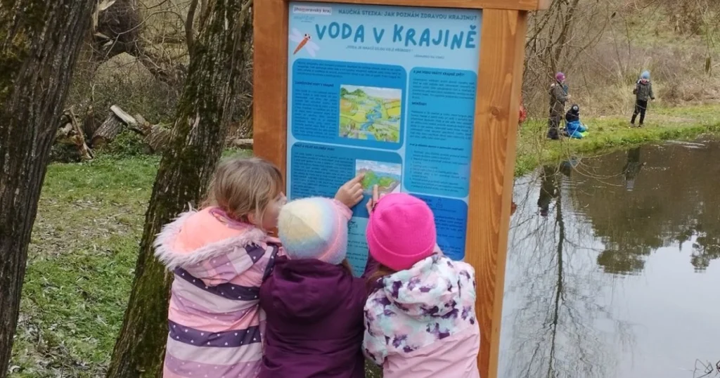 Děti ze ZŠ si prohlíží tabuli naučné stezky